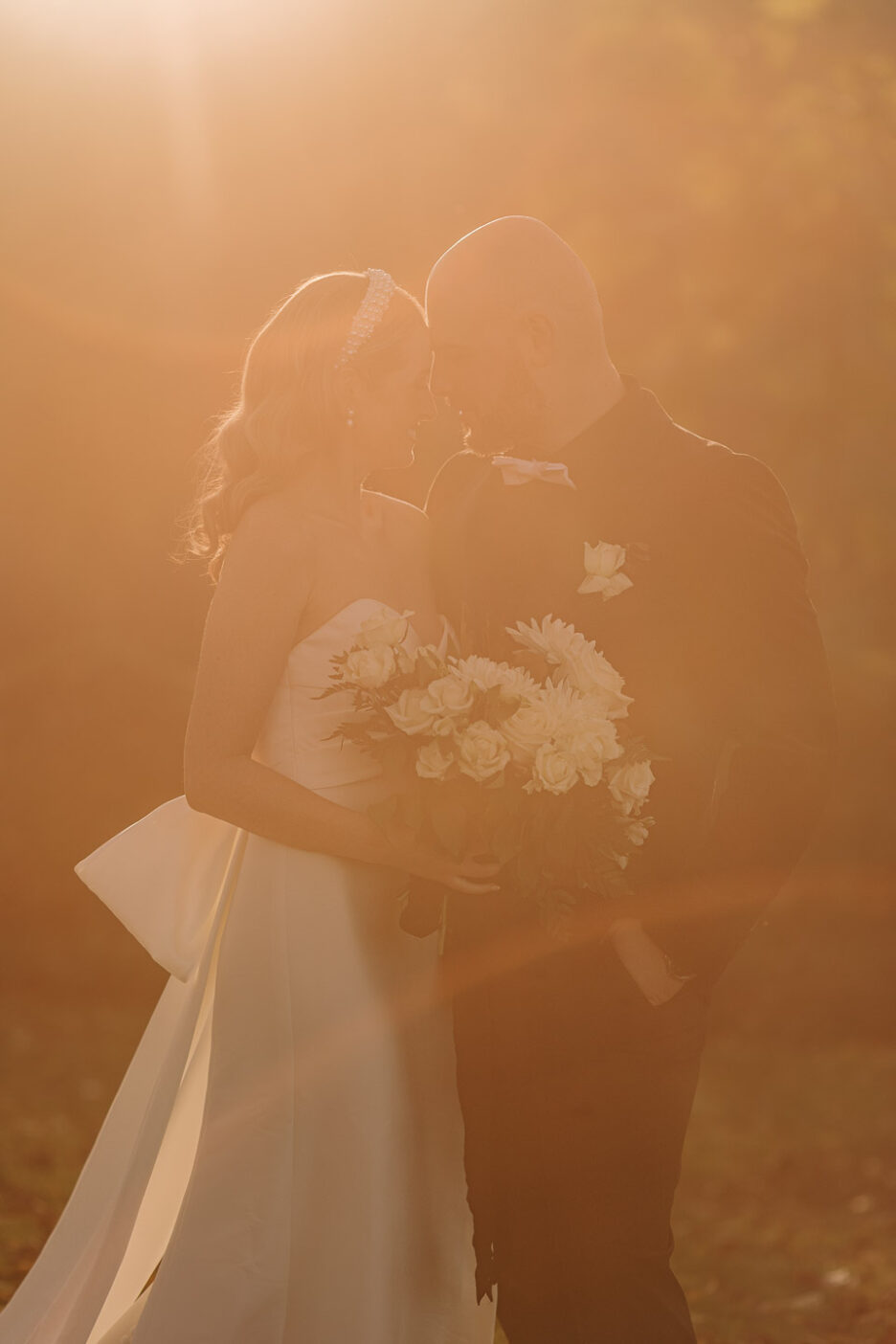 beautiful picture of bride and groom cuddling in golden light heads together