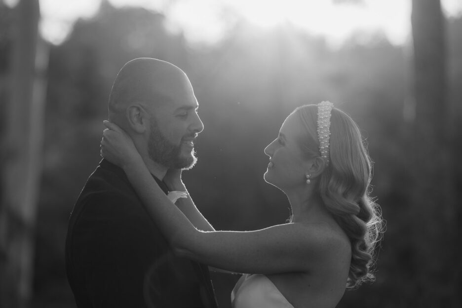 black and white image of bride holding her hands around her grooms neck