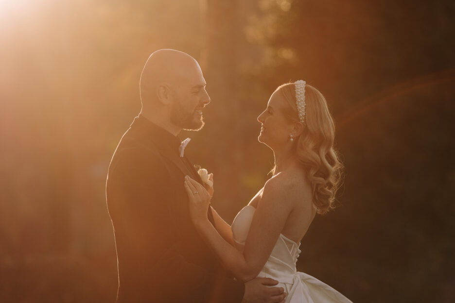 golden light with bride and groom looking at each other as sunsets behind