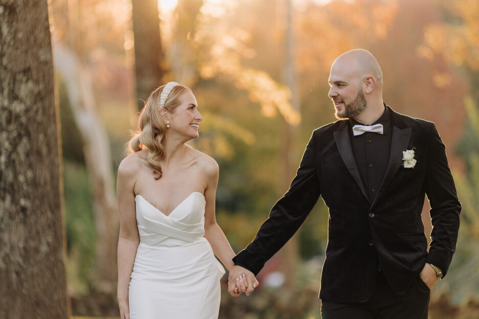 couple walk happily in golden light at black walnut Tauranga wedding venue