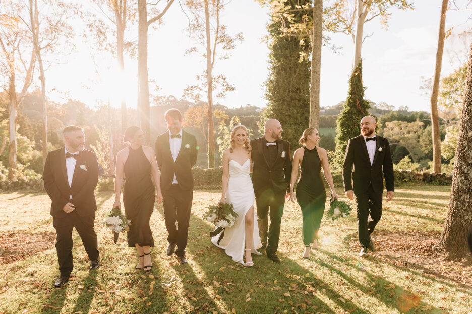 wedding party in black walks woodlands grounds in golden sunlight