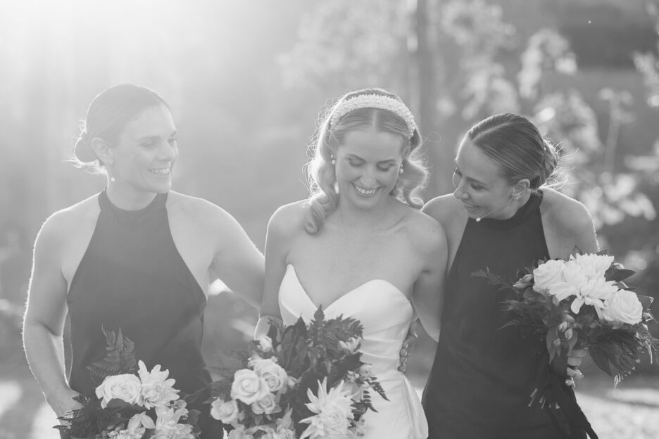 black and white photo of bride walking happy with bridesmaids in evolution black dresses