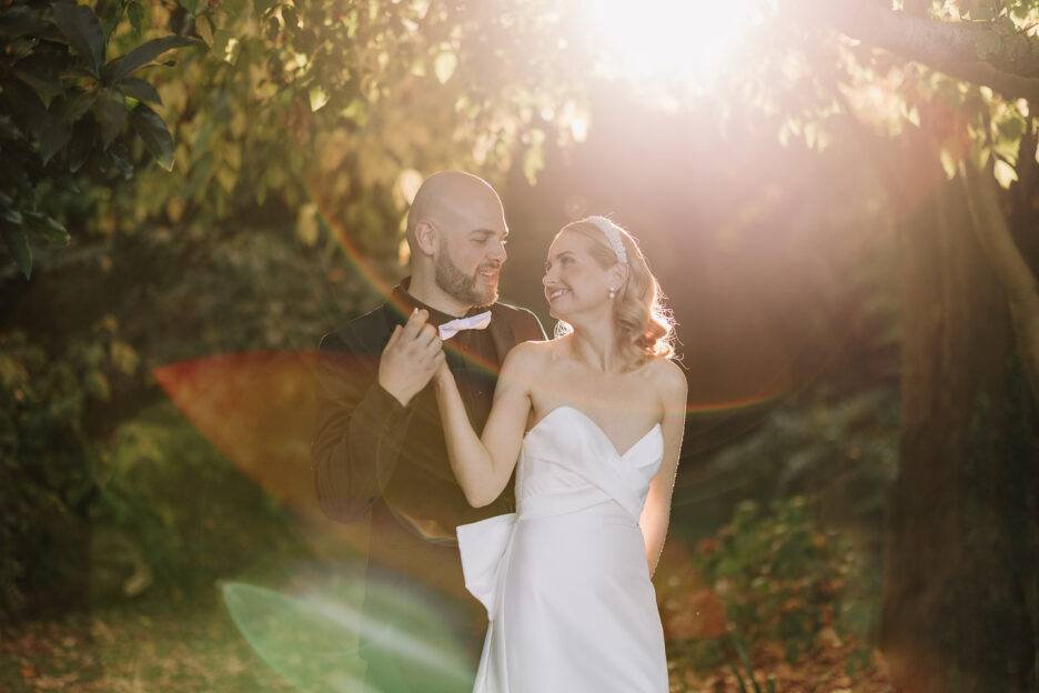 sunlight sneaks through the tree bride cuddles groom