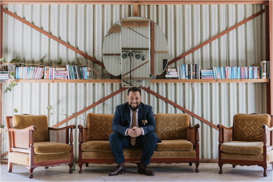 Groom seated on vintage seating in packing shed