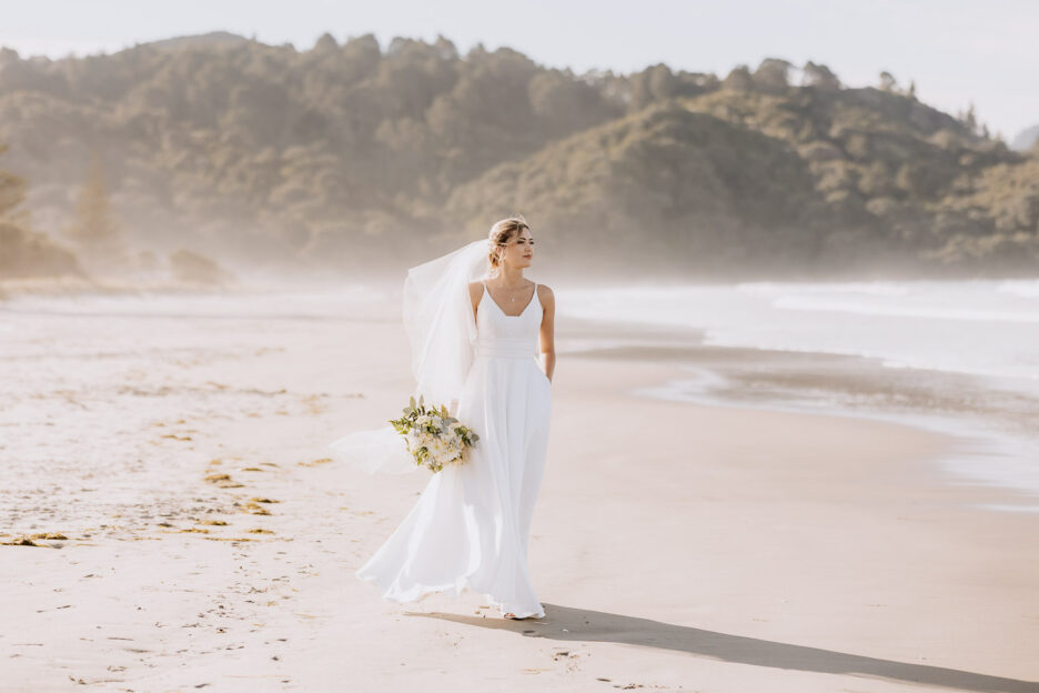 beautiful bride walking with hands in pockets waihi beach wedding