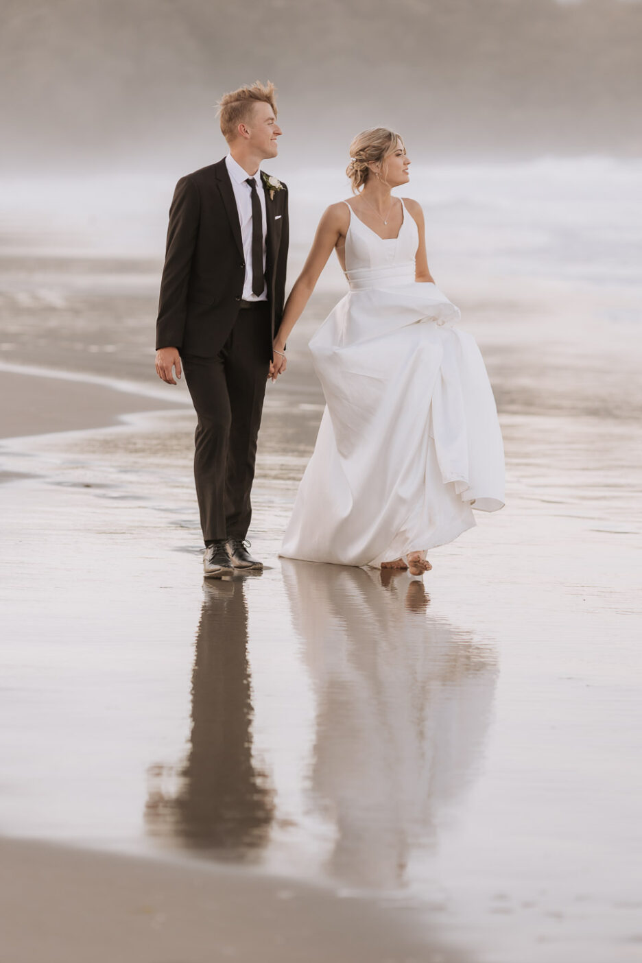 bride and groom looking out to sea as walking waihi beach