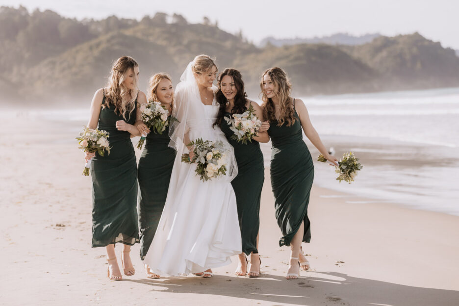 bride walking on waihi beach with bridesmaids