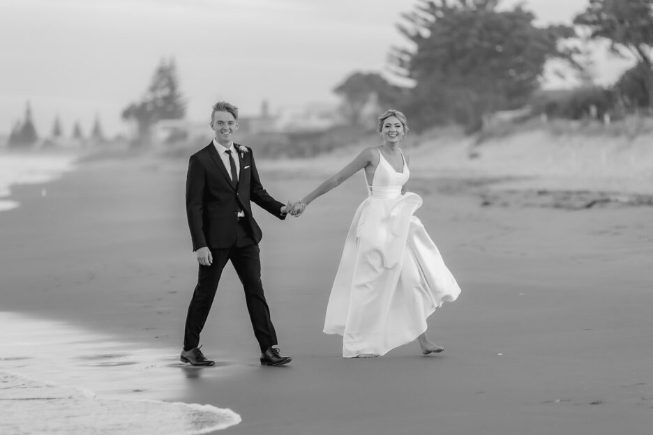 bride and groom laugh as runs away from water during their wedding photography