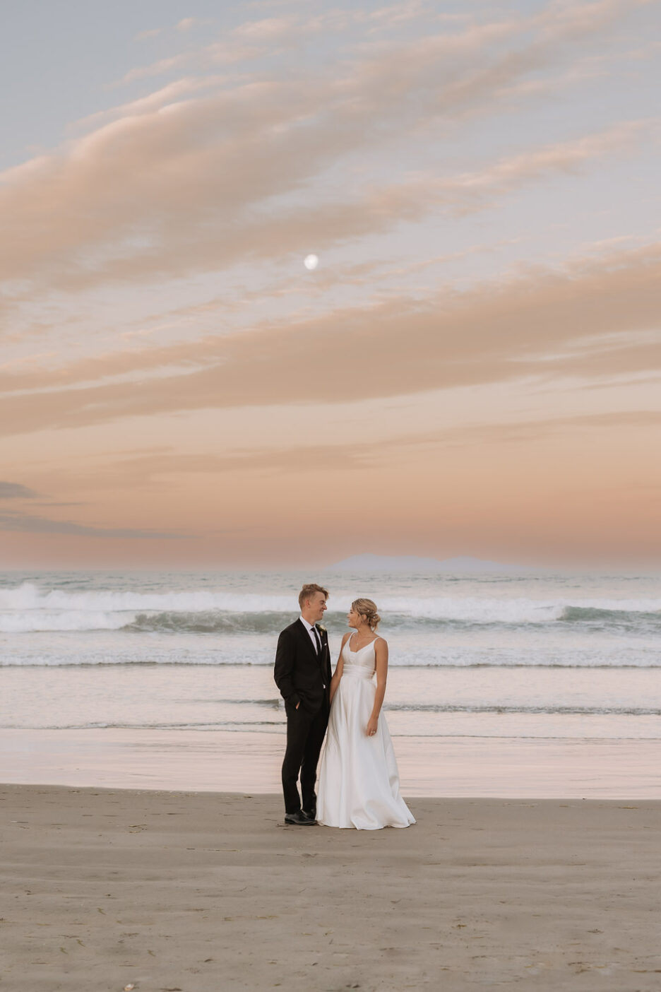 golden hour on waihi beach pastel sky during wedding photos