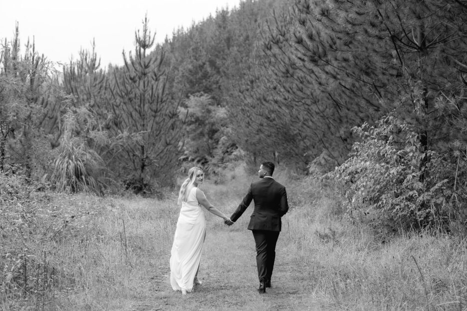 bride looks over should walking with husband on country forest lane