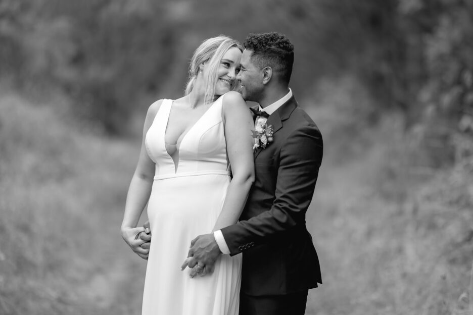 bride and groom in embrace smiling at eachother