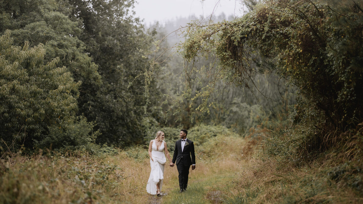 beautiful photo of bridal couple walking on forest lane with fog creeping over the trees