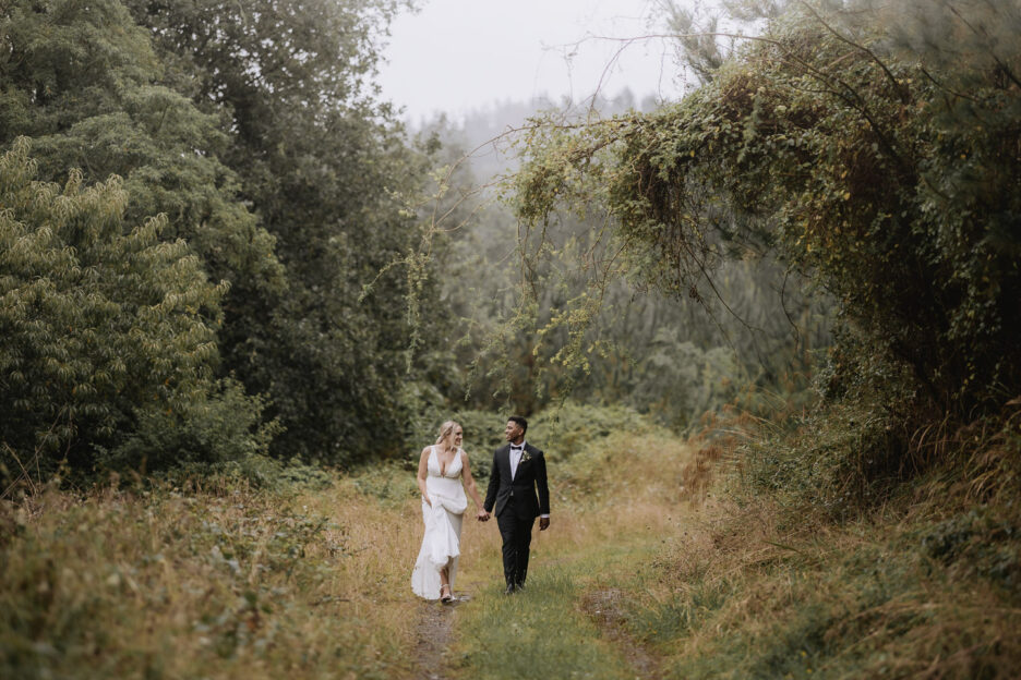 beautiful photo of bridal couple walking on forest lane with fog creeping over the trees