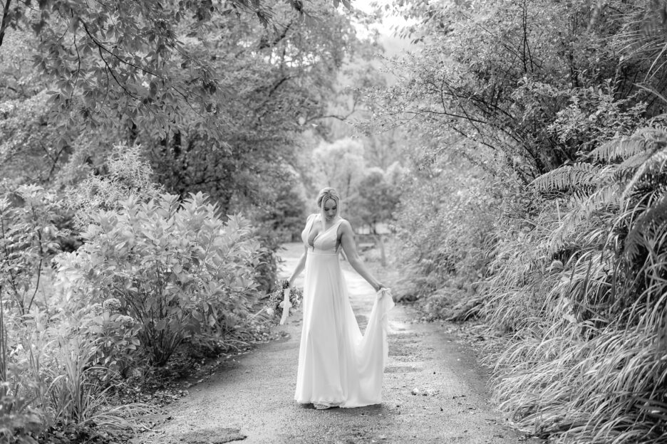 bride holding her train in contemplative moment on driveway