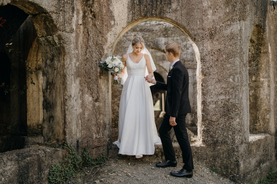 groom helps bride walk in ruins Victoria Battery