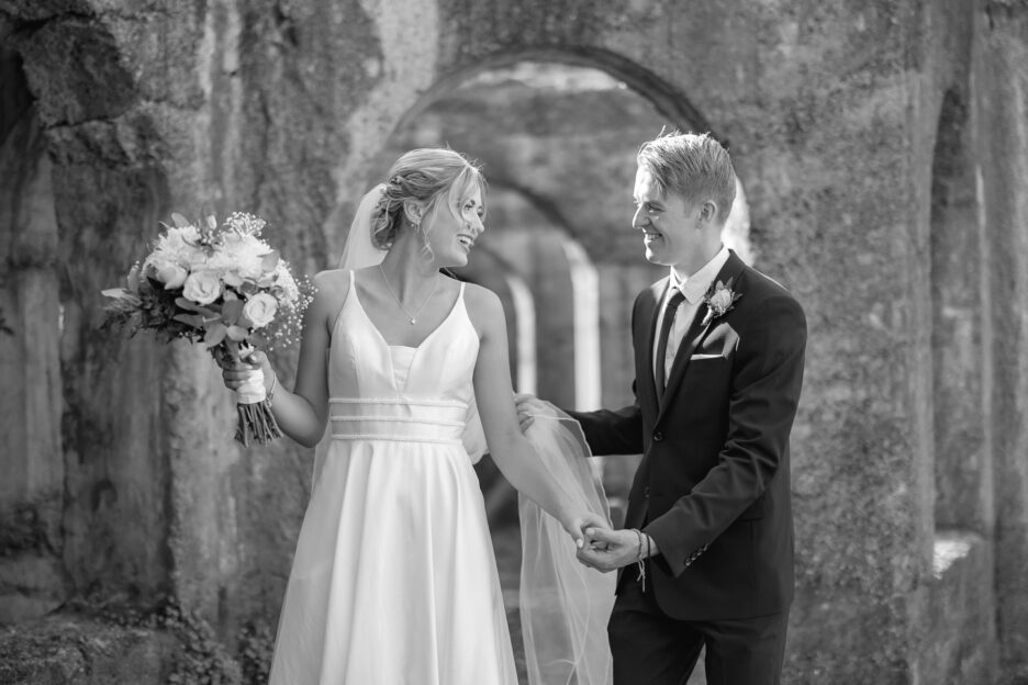 groom and bride walking laughing with historical ruins behind them