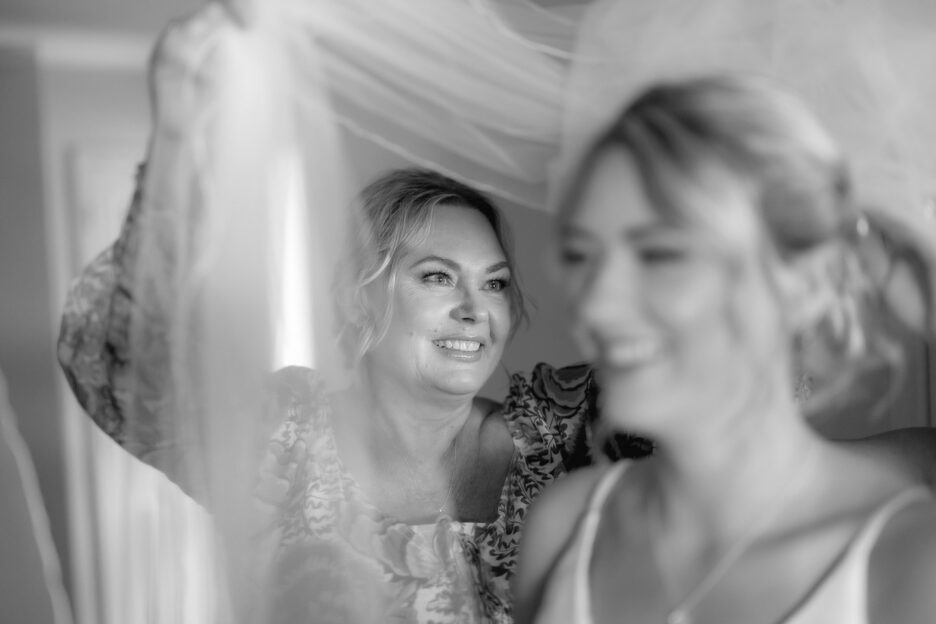 mother of bride holds her daughters veil smiling