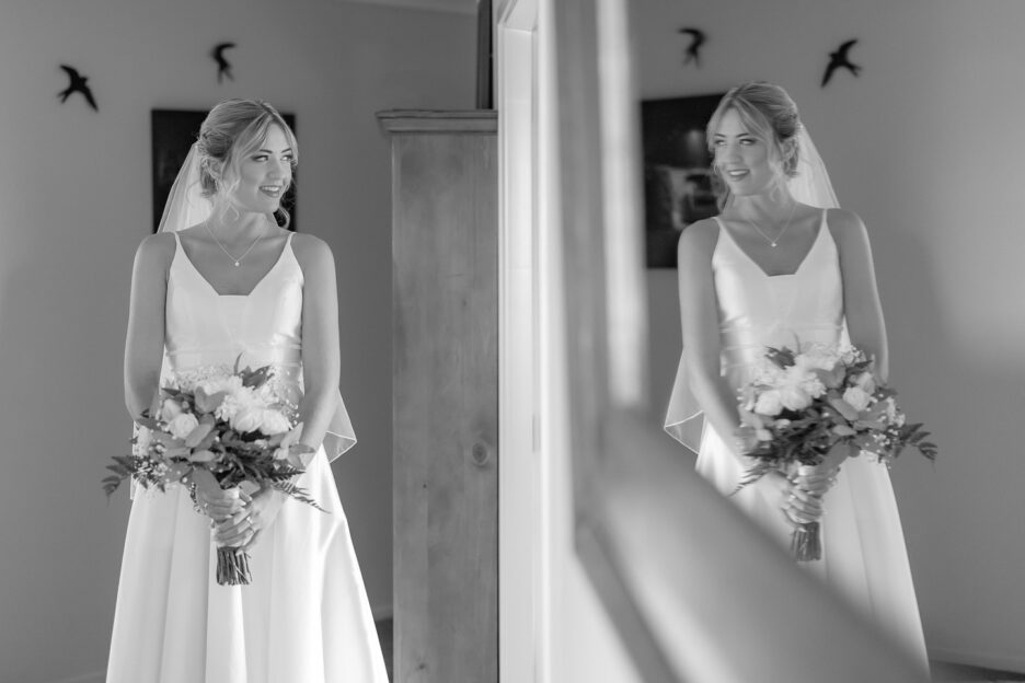 bride in hallway of home before wedding looking into mirror