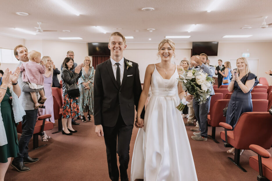 Happy couple walk down the aisle guests clapping