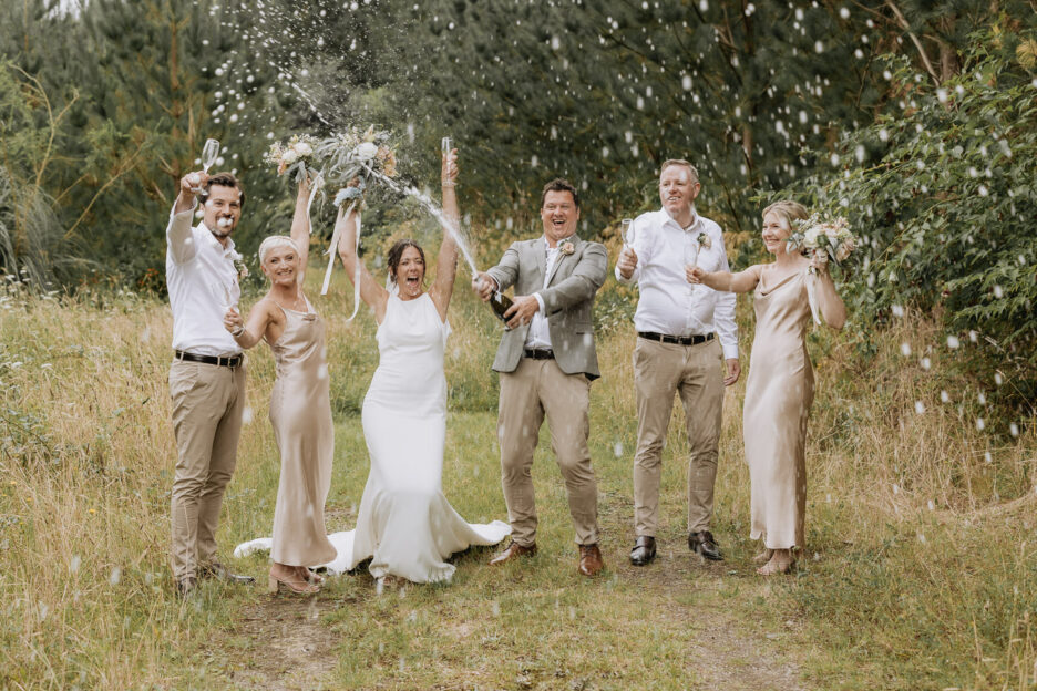 wedding party squirting champagne in forest