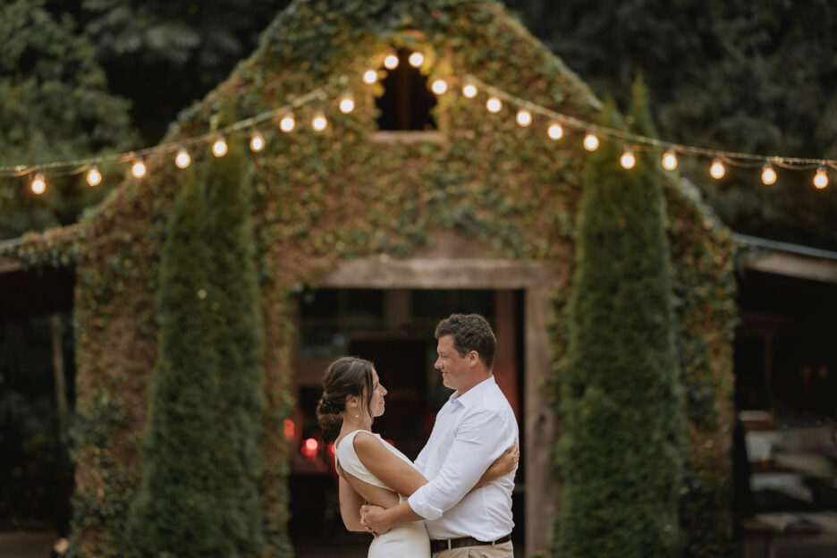 Wedding photo at dusk outside with fairy lights at old forest school