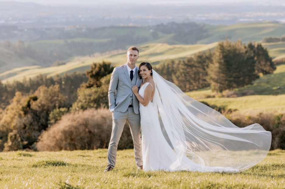 beautiful wedding photo of couple on field with brides veil flying