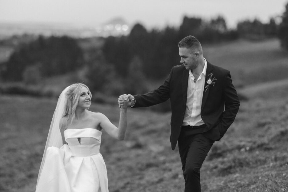 moment between wedding couple walking at dusk hills above tauranga