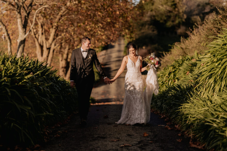 Happy bride and groom walk in autumn light Eagle Ridges driveway