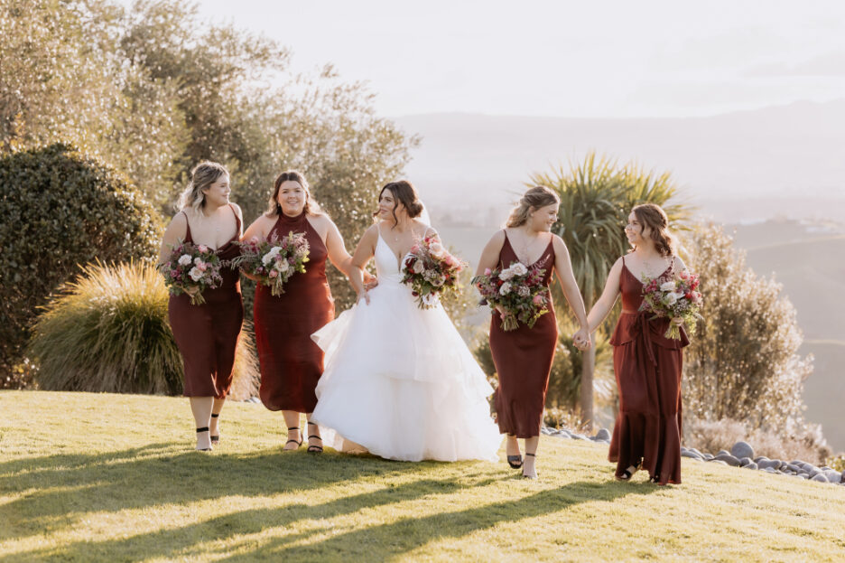 beautiful bridesmaids in wine dresses with bride walking in late summer light