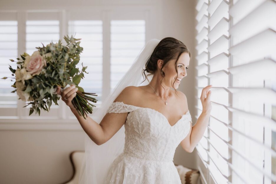 bride peeks at guests from window