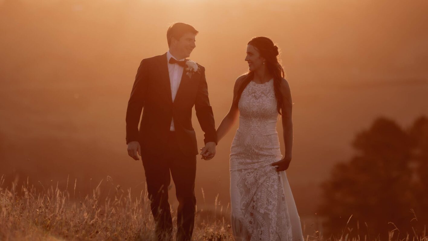 Bride and groom walking on hills at sunset