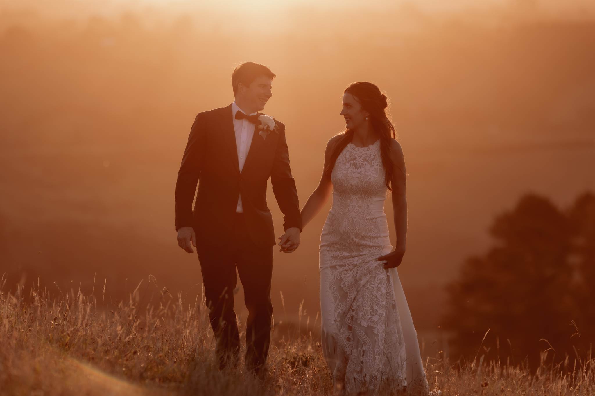 Bride and groom walking on hills at sunset