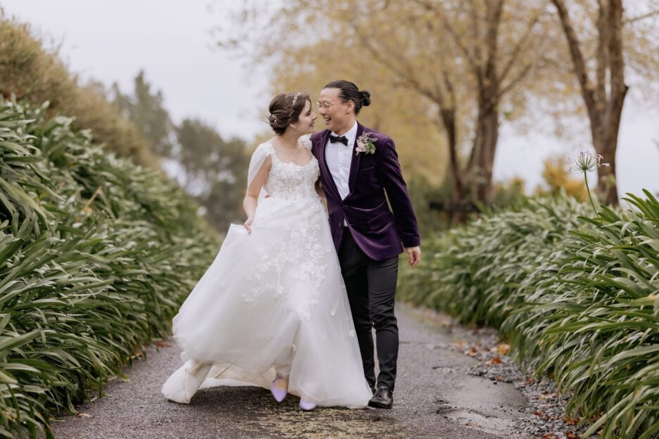 Groom in purple jacket and bride celebrating as they walk eagle ridge driveway